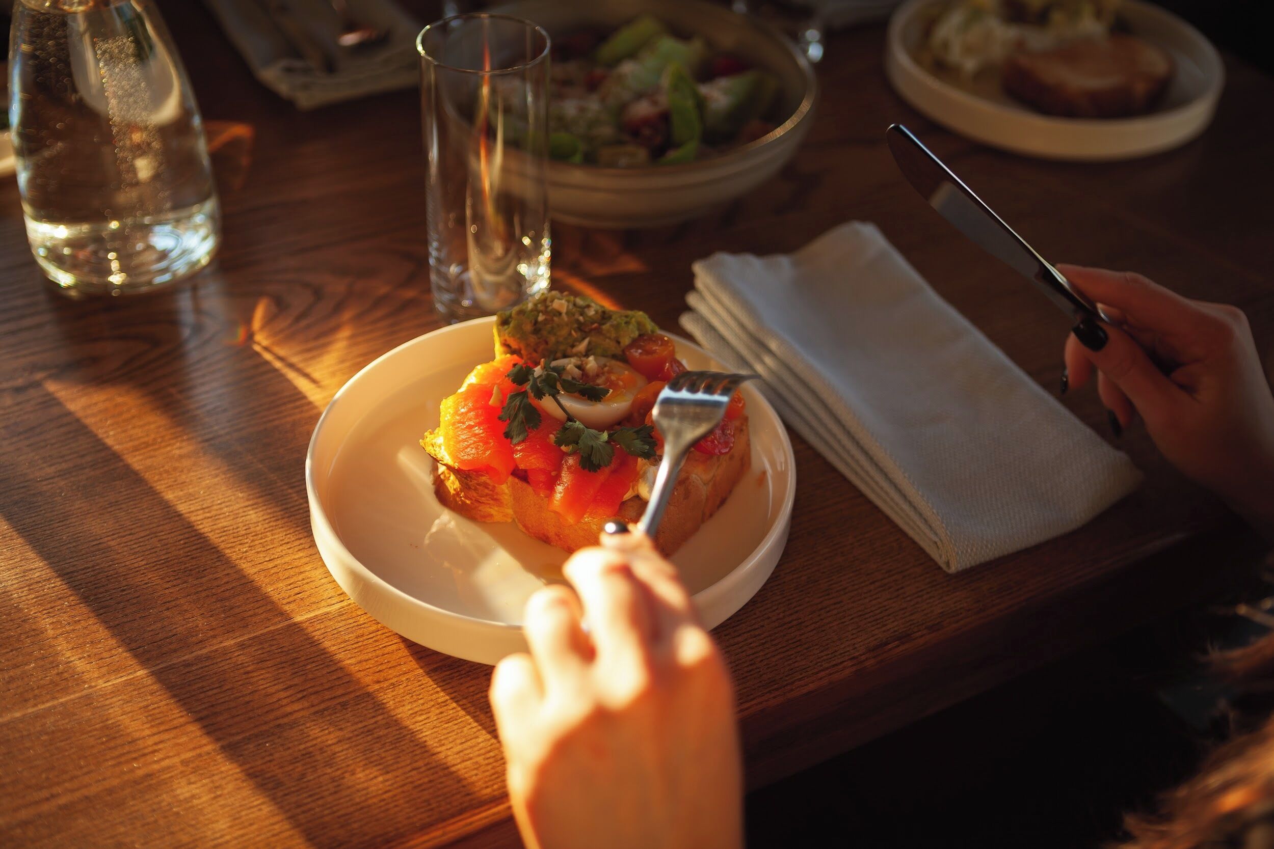 A dining table with a plate of food, a glass of water, and a fork.