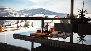 A table with a glass top, a pitcher, and cups, set against a snowy mountain backdrop. - EcoBerghaus (Bukovel)
