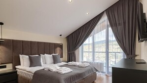 Een moderne slaapkamer met een groot bed, een flatscreen televisie en uitzicht op de omgeving.