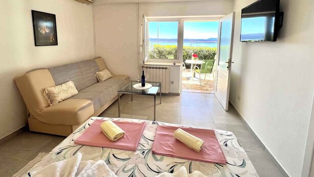 A modern living room with a sofa, a glass coffee table, and a view of the outdoors. - Apartman Kate 1 (Dramalj)