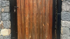 Un cancello in legno affiancato da un muro in pietra, con una maniglia metallica e una serratura.