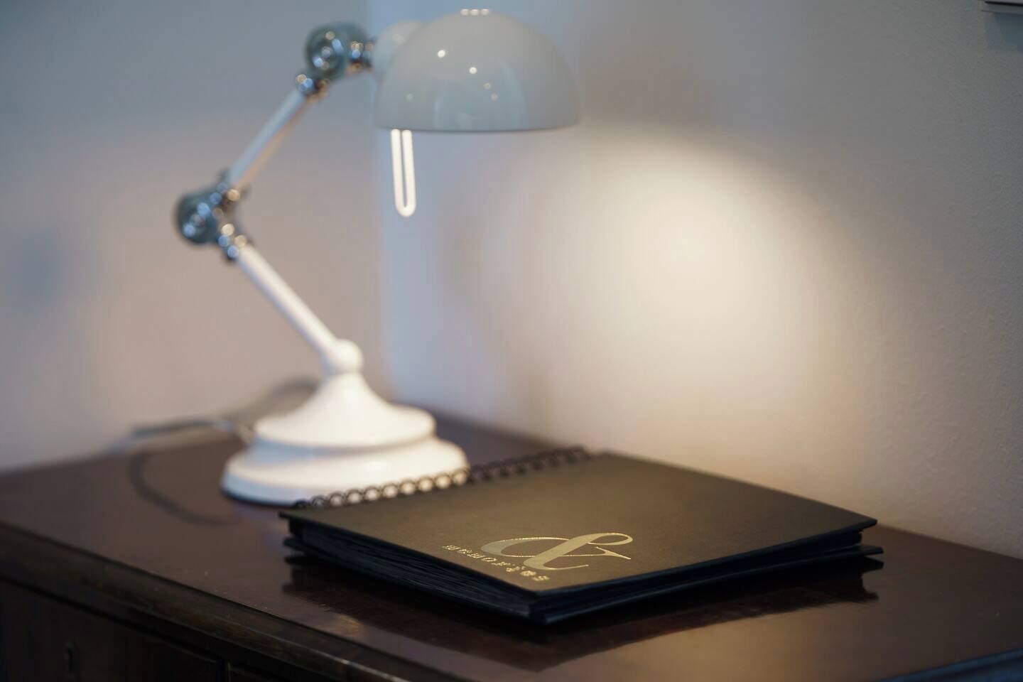 Ein Schreibtisch mit geschlossenem Notizbuch und einer Schreibtischlampe.