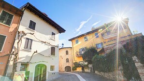A narrow cobblestone street with historic buildings, a sign indicating a no parking zone, and a clear blue sky. - Lory-cosy Gardone Old Town&vittoriale (Gardone Riviera)