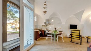 A modern kitchen with a dining area, large windows, and a TV mounted on the wall. - Lory-cosy Gardone Old Town&vittoriale (Gardone Riviera)