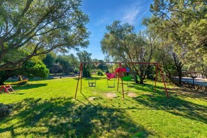 Un parco con altalene, uno scivolo e un'area picnic.