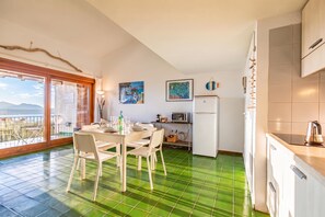 Una cucina con zona pranzo, un frigorifero e vista attraverso una porta in vetro.