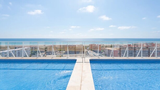 Piscina con vistas despejadas a la playa y edificios al fondo.