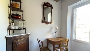 Un comedor con mesa y sillas de madera, un armario con vajilla, un espejo y una ventana con vistas.