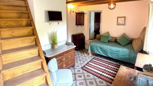 Una habitación acogedora con una escalera de madera, una cama con almohadas verdes, un escritorio con una planta y una alfombra estampada.