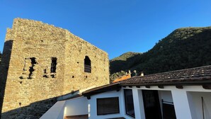Un edificio de piedra con techo de tejas y una estructura blanca contigua.