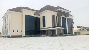 A modern two-story building with a symmetrical facade, large windows, and a central entrance with steps. - Global Luxury Suites (Kano)