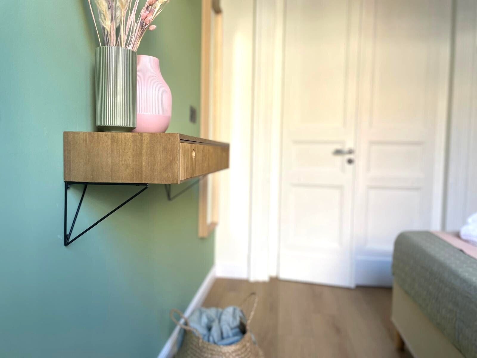 Una habitación con un estante de madera que sostiene un jarrón y una cesta.