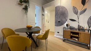 A dining area with a round table, yellow chairs, and a wooden cabinet with a vase.