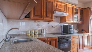 Eine Küche mit Granit Arbeitsplatten, Holzschränken, einer Edelstahlspüle, einer Kaffeemaschine und einem Geschirrspüler.