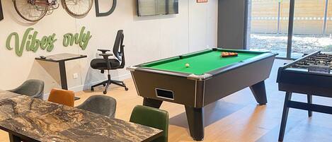 A pool table, chairs, a table, a bicycle, and a wall with a sign saying "This is my happy place".