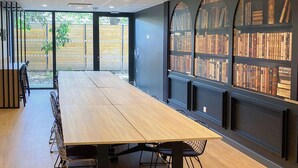 A conference room with a long table, chairs, and a bookshelf with books. - Nemea Appart Hotel Strasbourg Illkirch (Illkirch-Graffenstaden)