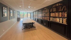 A library with a long table and bookshelves. - Nemea Appart Hotel Strasbourg Illkirch (Illkirch-Graffenstaden)