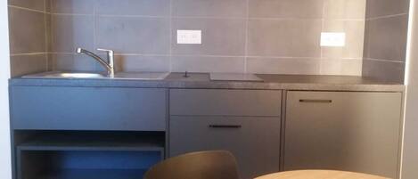 A compact kitchen with a sink, cabinets, and a dining area with a table and chairs.