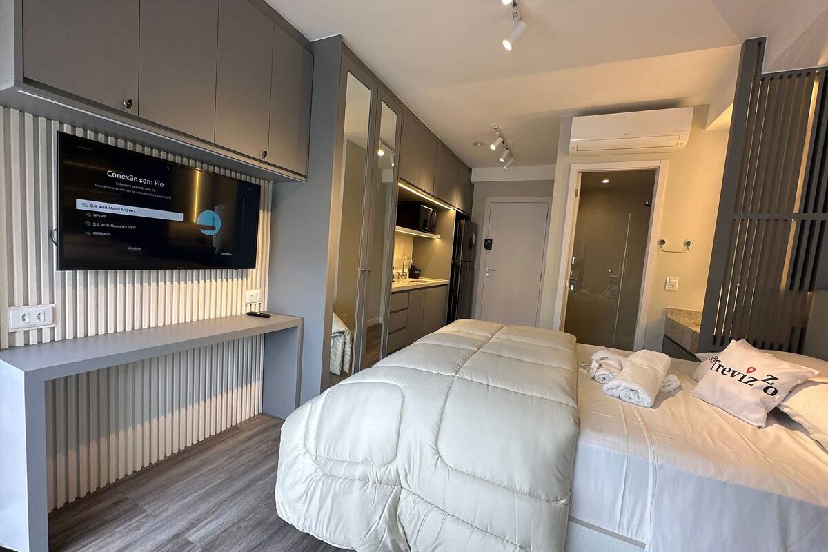 Une chambre d’hôtel moderne avec un grand lit, un téléviseur fixé au mur et une armoire avec des portes coulissantes.