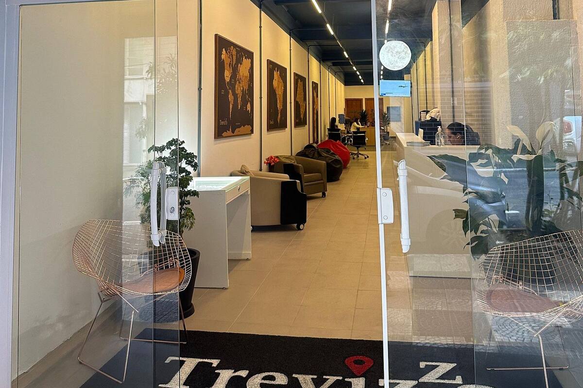 L’entrée d’un hôtel appelé Treviso, avec un comptoir d’accueil, un espace salon et des cartes du monde accrochées aux murs.