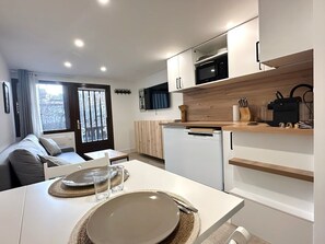 Een moderne keuken met witte kasten, een houten aanrechtblad en een inbouwmagnetron.