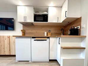 Een moderne keuken met witte kasten, een magnetron, een vaatwasser en houten aanrechtbladen.