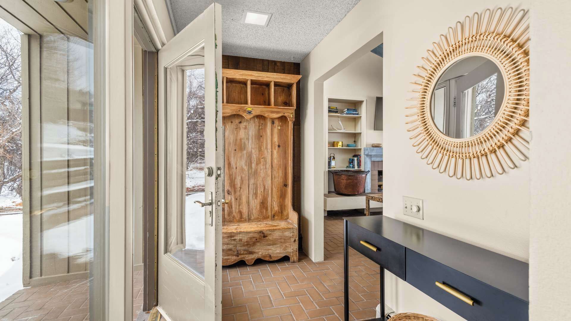 A bathroom with a wooden bench, a round mirror, and a black vanity.