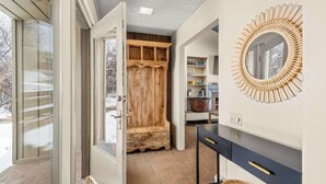 Une salle de bain avec un banc en bois, un miroir rond et un meuble-lavabo noir.