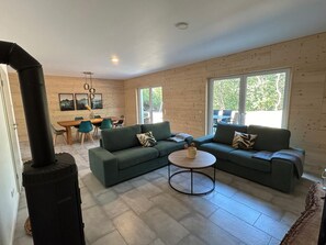 Cozy living space with a wood-burning stove, comfortable L-shaped sofa, and a dining area.