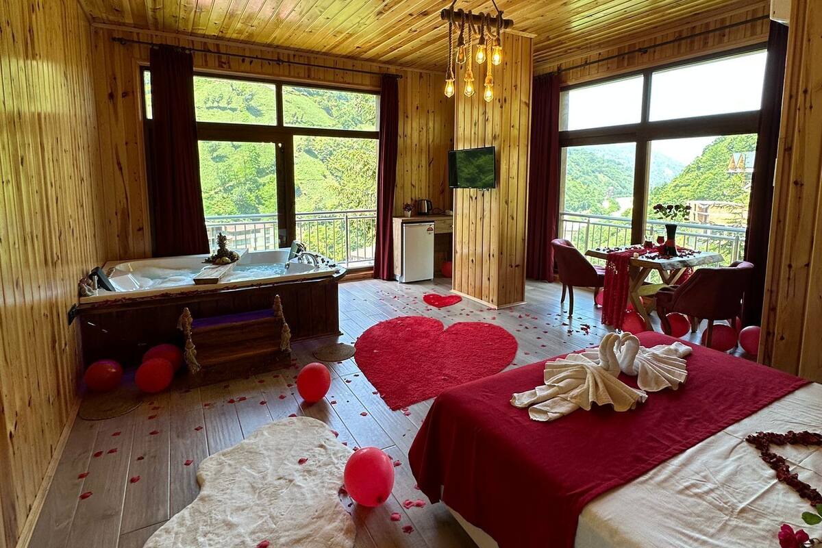 Une cabane en bois avec un grand lit, une baignoire et un coin repas.