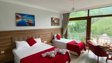 A hotel room with two beds, a red and white color scheme, a large window with a view of greenery, and a small balcony.