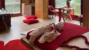 Habitación tipo cabaña de madera con cama, escritorio, silla y balcón con vistas a las montañas.