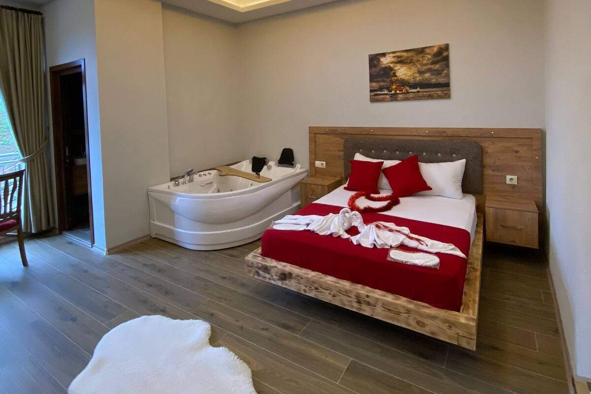 Une chambre moderne avec un grand lit, une baignoire et un luminaire au plafond.