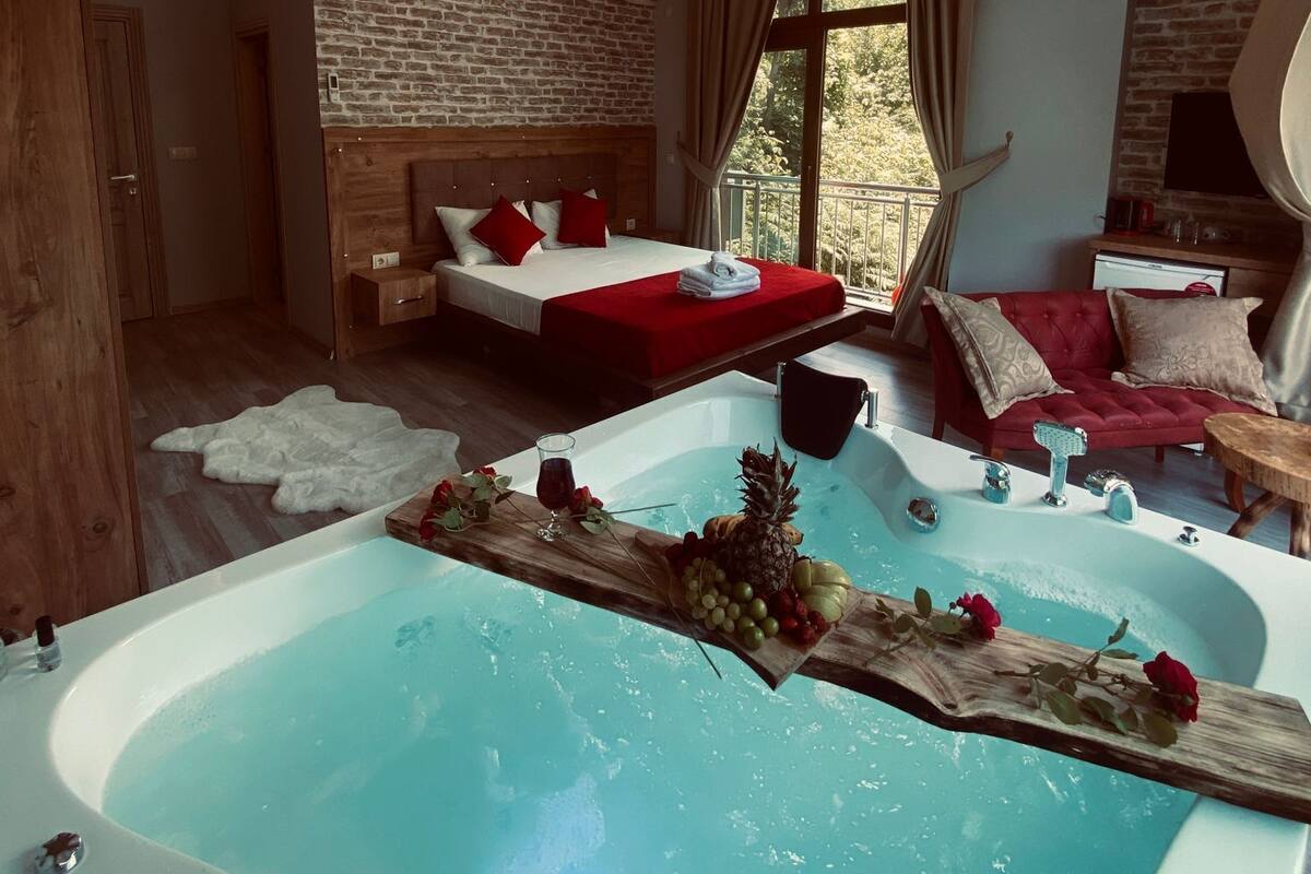 Une chambre d’hôtel moderne dotée d’une grande baignoire, d’une chambre à coucher séparée et d’un coin salon confortable.