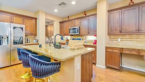 A kitchen with wooden cabinets, a granite countertop, and a stainless steel refrigerator. - Pool, Movie Room, Games, Grill! (Goodyear)