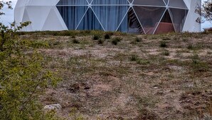 A geodesic dome structure with a large central window and a smaller circular window on the side.