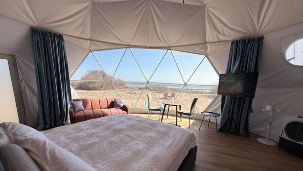 A spacious tented room with a large bed, a TV, and a fan.