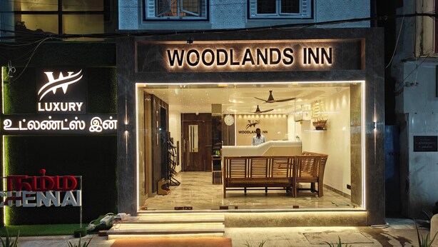 L’extérieur de l’hôtel Woodlands Inn se distingue par son comptoir d’accueil, un espace salon avec un banc et des plantes en pot à l’entrée.