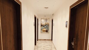 Un couloir avec des portes en bois, un sol en marbre et un tableau accroché au mur.