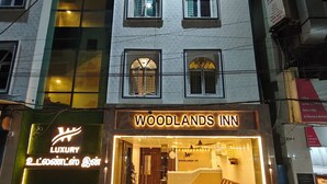 Un hôtel appelé « Woodlands Inn », reconnaissable à son enseigne, son comptoir d’accueil et son espace détente, qui sont visibles depuis l’entrée.