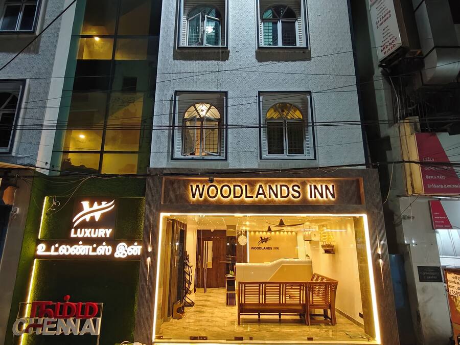 Um hotel chamado "Woodlands Inn", com uma placa, uma receção e uma área de estar visível pela entrada.