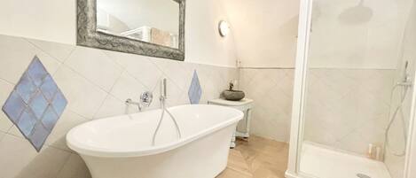 A bathroom with a freestanding bathtub, a sink, a mirror, and a glass-enclosed shower.