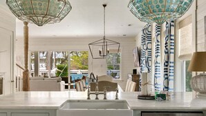A modern kitchen with a central island, pendant lights, and a view of the outdoor dining area. - 6-Seater LSV & Bikes Included! Private Pool, 2 Kings, Pet Friendly! Seagrove Eastern Lake! (Santa Rosa Beach)