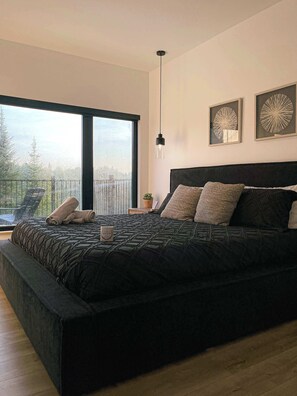 Une chambre moderne avec un grand lit, une suspension et deux œuvres d’art murales.