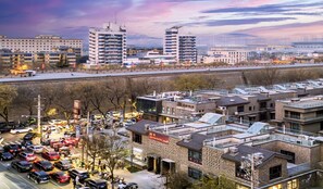 A hotel with multiple floors, a parking lot, and a view of the cityscape in the background. - Xiyou Hotel XIan City Wall Branch (Xi'an)