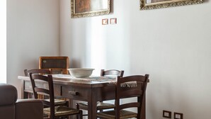 Un comedor con una mesa y sillas de madera, dos cuadros enmarcados en la pared y un techo con vigas a la vista.