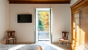 Een slaapkamer met een bed, twee stoelen, een televisie en een houten garderobe.