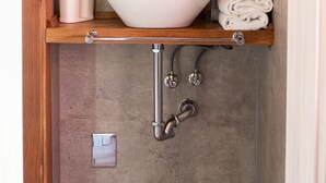 Une salle de bain avec un lavabo sur colonne blanc, un miroir au-dessus et un porte-serviettes avec des serviettes.