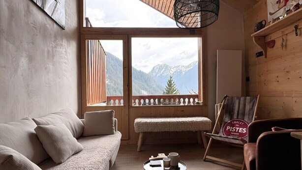 Une pièce chaleureuse avec un plancher en bois, un canapé, un banc et une table sur laquelle se trouve un plateau.