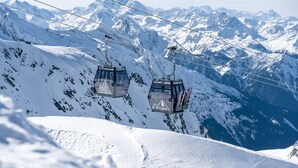 Un télésiège dans une région montagneuse enneigée, sous un ciel dégagé.